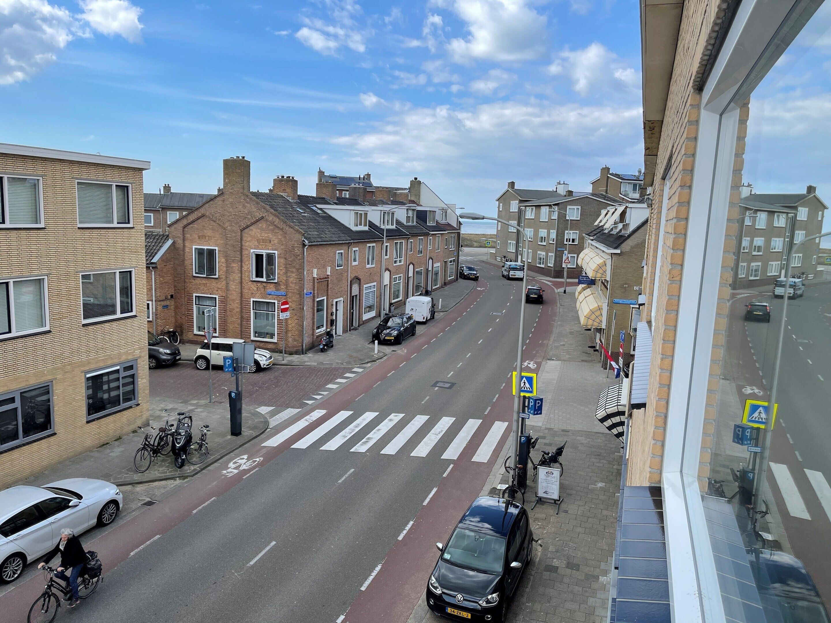 Une vue de rue avec un passage piéton, des voitures garées et des vélos.