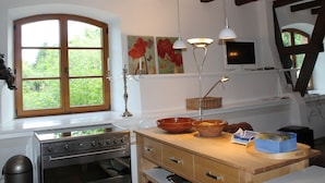 A kitchen with a stove, wooden cabinets, a window, and a painting on the wall. - Mansion in Gressow With Terrace, Garden, Bbq, Pond, Bicycles (Gaegelow)
