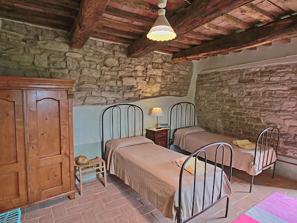 A rustic room with stone walls, two metal beds, a wooden wardrobe, and a hanging light fixture. - Spacious Farmhouse in Apecchio With Pool (Apecchio)