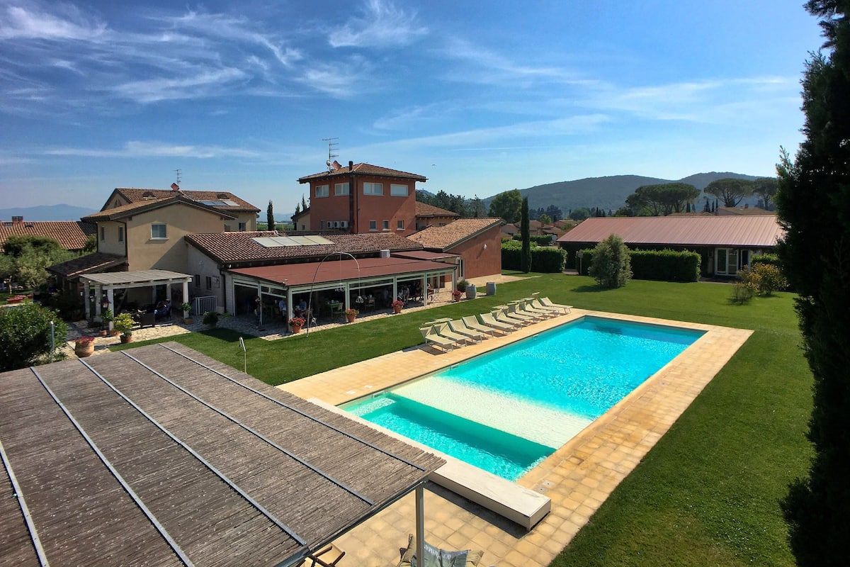 A residential property with a swimming pool, a covered patio, and a view of the surrounding landscape.
