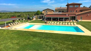 A large swimming pool with lounge chairs, a covered patio, and a view of the surrounding landscape.