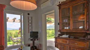 A room with a wooden dining table, chairs, a television, and a cabinet with glass doors.