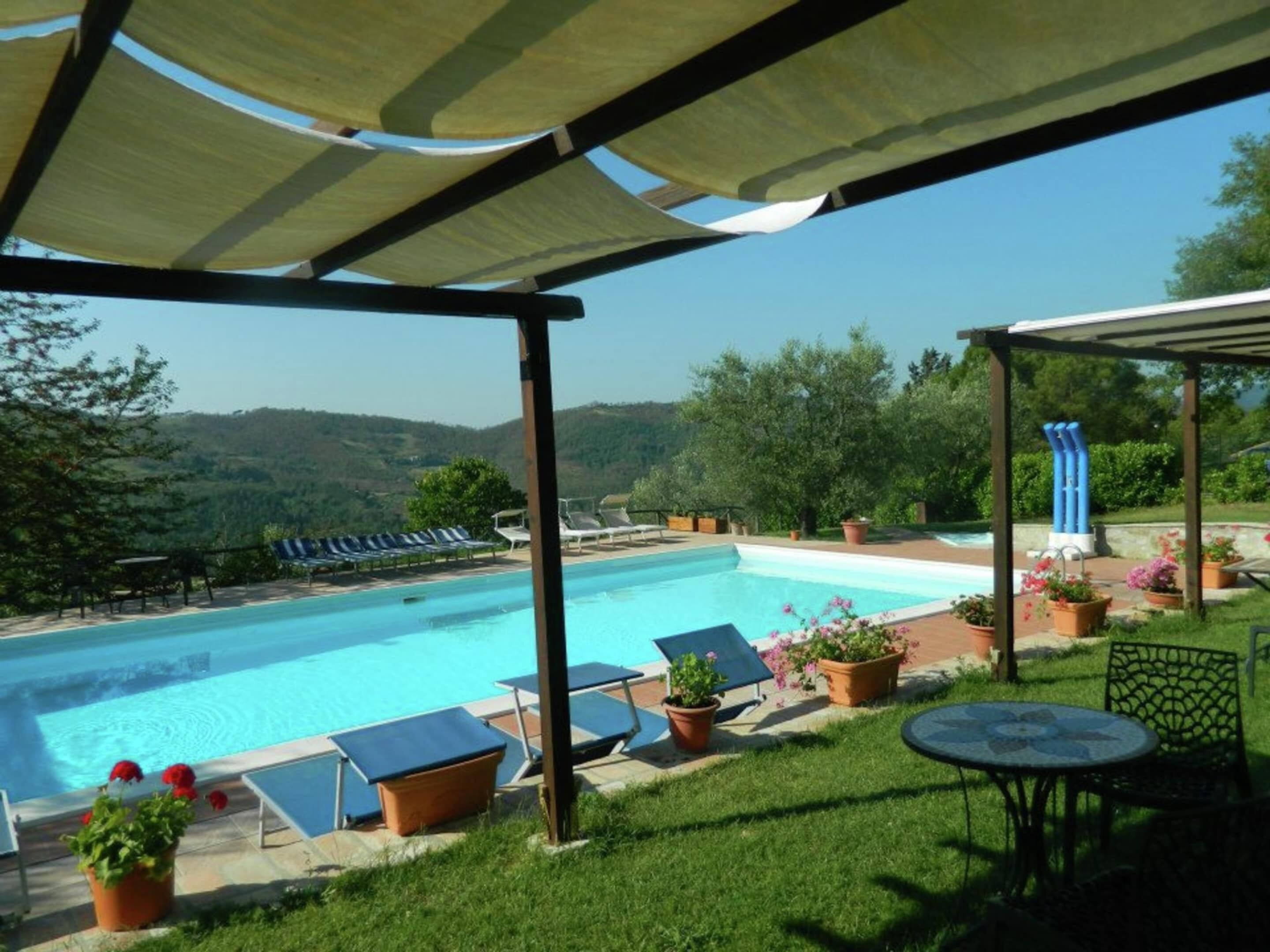 A pool area with lounge chairs and a view of hills.