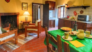 A cozy kitchen with a dining area, featuring a fireplace, wooden furniture, and a green tablecloth. - Farmhouse With Stables, Horses and the Ability to Make Horseback Riding (Monte Santa Maria Tiberina)