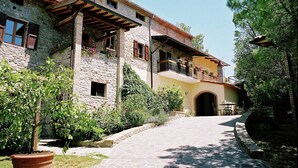 A stone building with a balcony, a door, and a pathway leading to it. - Farmhouse With Stables, Horses and the Ability to Make Horseback Riding (Monte Santa Maria Tiberina)