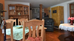 Un área de comedor con sillas de madera y una mesa, una cocina al fondo y una pared de acento amarilla.