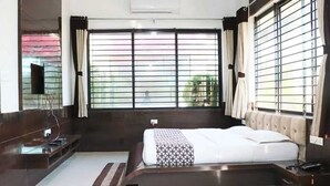 Un dormitorio moderno con una cama grande, una mesita de noche, un televisor y una ventana con persianas.