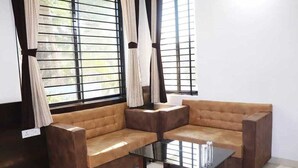 Un rincón con cojines y una zona de estar con sofá marrón y una mesa de centro de vidrio.