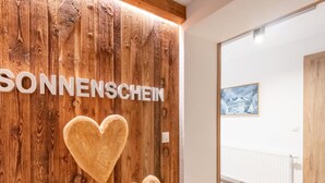 Pared de madera con el texto "SONNENSCHEIN" y dos adornos con forma de corazón.
