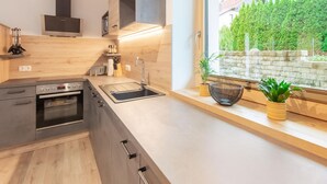 Una cocina moderna con horno empotrado, un fregadero y ventana con vistas a un jardín.