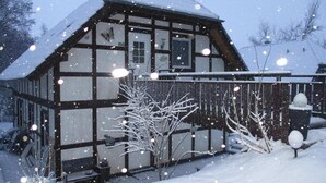 A traditional timber-framed house with a snow-covered roof and a visible number '140' on the facade.