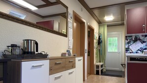 A kitchen with a stove, sink, and cabinets. There is a mirror above the counter and a door leading to another room.