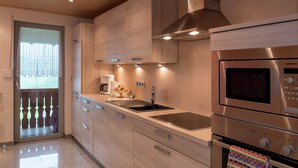 Una cocina moderna con electrodomésticos de acero inoxidable, armarios de madera y un amplio ventanal con vistas.