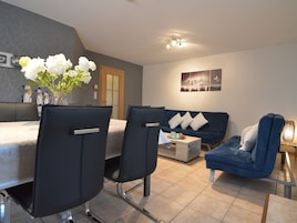 Una sala de estar moderna con un sofá, dos sillones, una mesa de centro y un comedor con mesa y sillas.