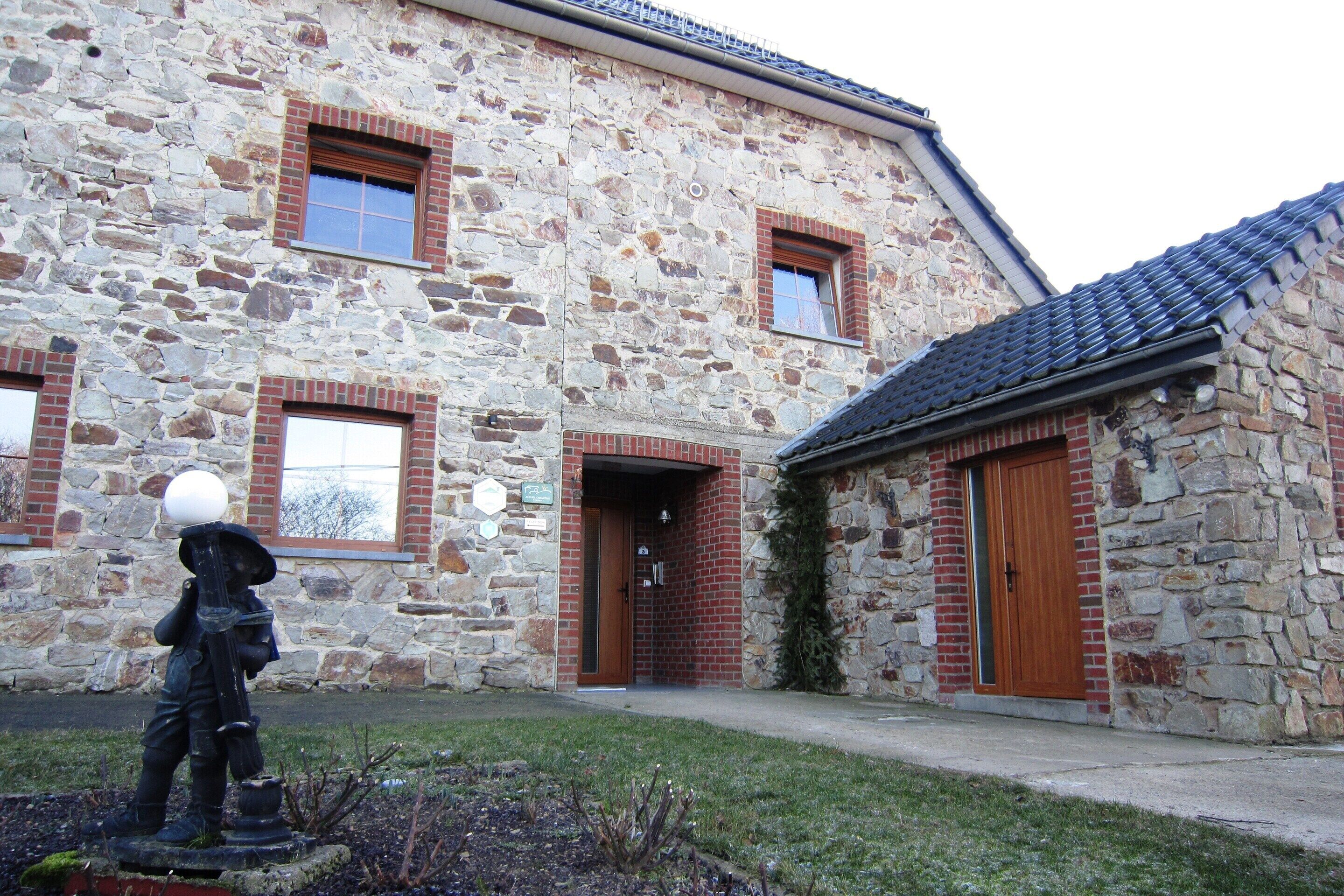 A stone building with a brick entrance and a small adjacent structure with a tiled roof.