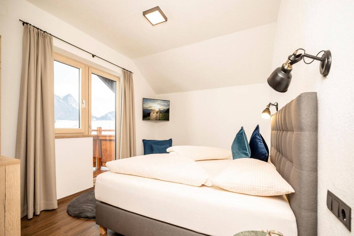 Une chambre à coucher avec un lit, une fenêtre avec des rideaux, un tableau au mur et une lampe de chevet.