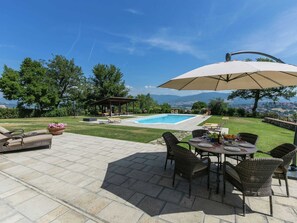 En terrasse med pool, udendørs møbler og udsigt til bjergene.