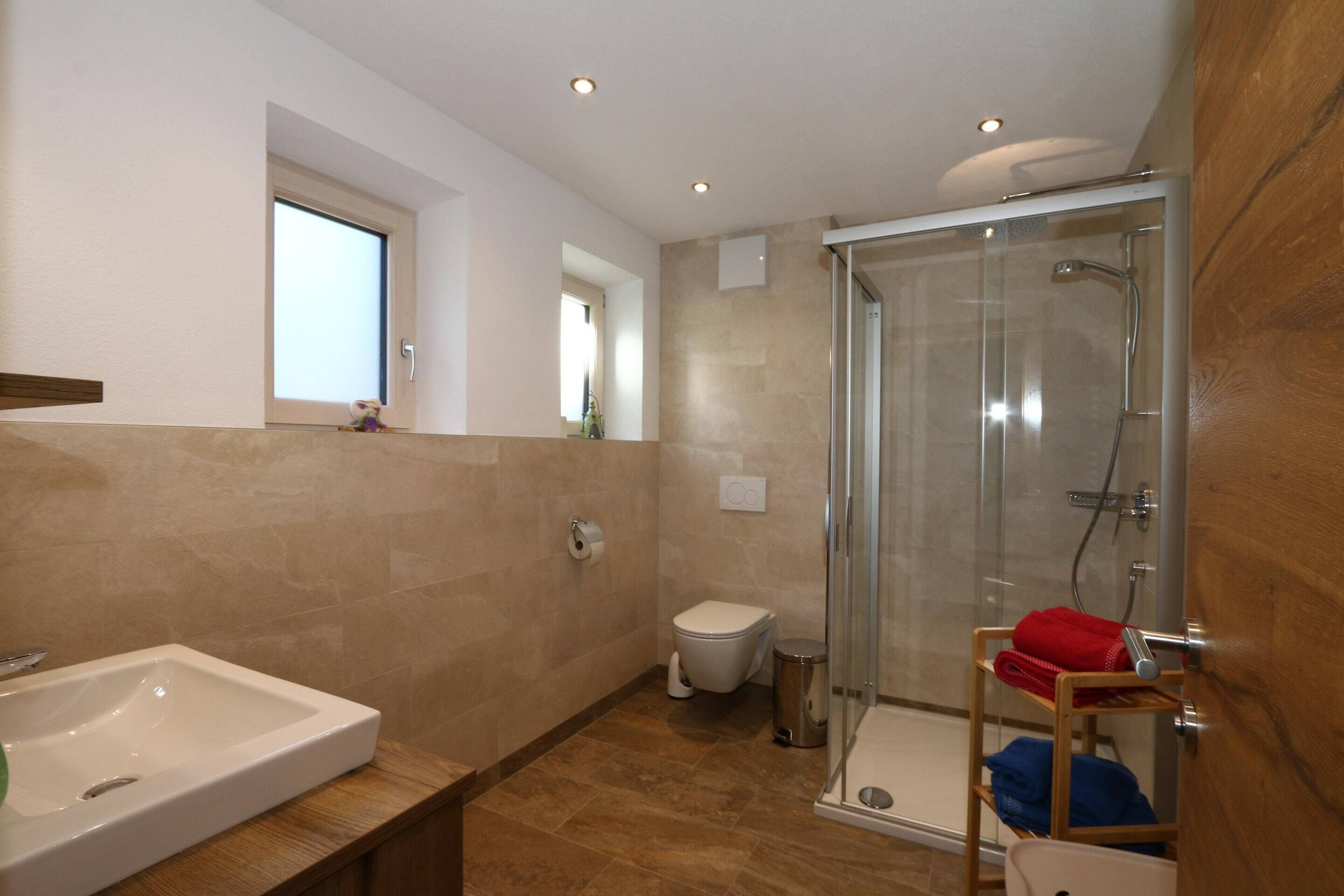 A modern bathroom with a large sink, toilet, and glass-enclosed shower.