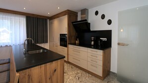 Una cocina moderna con armarios de madera, encimera negra y pileta de acero inoxidable.
