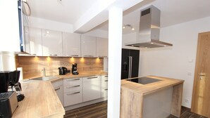A modern kitchen with white cabinets, a wooden countertop, and a stainless steel range hood. - Modern Chalet With Sauna Near ski Area in Saalbach-hinterglemm / Salzburgerland (Saalbach-Hinterglemm)