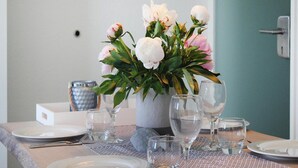 A dining table set with plates, cutlery, and wine glasses, with a vase of flowers in the center. - Apartment in Ostseeresort Olpenitz With Balcony (Kappeln)