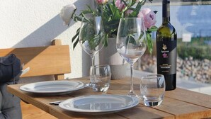 A wooden table set with plates, glasses, and a bottle of wine, accompanied by a vase of flowers. - Apartment in Ostseeresort Olpenitz With Balcony (Kappeln)