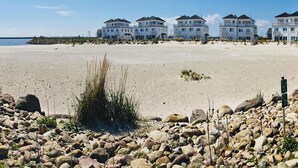 A beachfront property with multiple white buildings, a sandy beach, and a rocky foreground. - Apartment in Ostseeresort Olpenitz With Balcony (Kappeln)