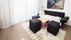 Uma sala de estar moderna com um sofá, dois pufes, uma mesa de centro e um quadro na parede.