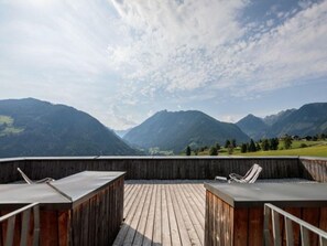 Una terraza de madera con dos sillones de descanso frente a un paisaje montañoso.