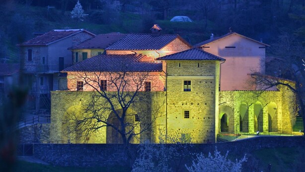 Un edificio storico con facciata in pietra, numerose finestre e un cortile centrale con archi.