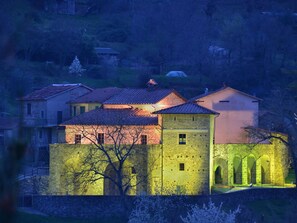 A historic building with a stone facade, multiple windows, and a central courtyard with arches. - Flat With Heated hot tub and Shared Pool (Casola in Lunigiana)