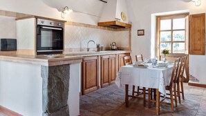 Una cucina con isola centrale, mobili in legno, forno integrato e zona pranzo con tavolo apparecchiato per quattro.