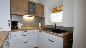 A compact kitchen with wooden cabinets, a black countertop, and a window with a curtain. - Apartment in Bramberg am Wildkogel With Parking Space (Bramberg am Wildkogel)