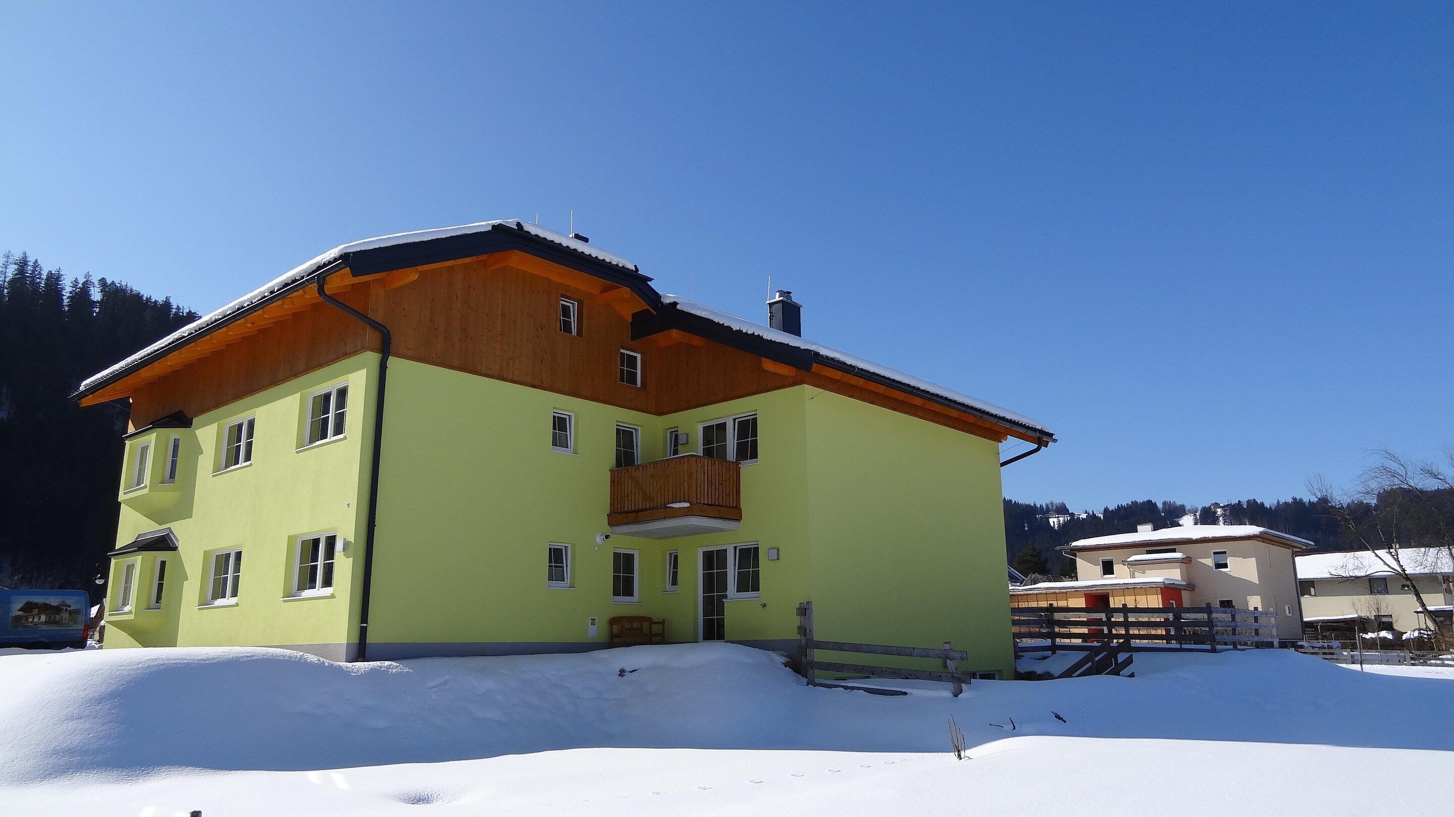 Un edificio de varios pisos con un balcón de madera, rodeado de nieve.
