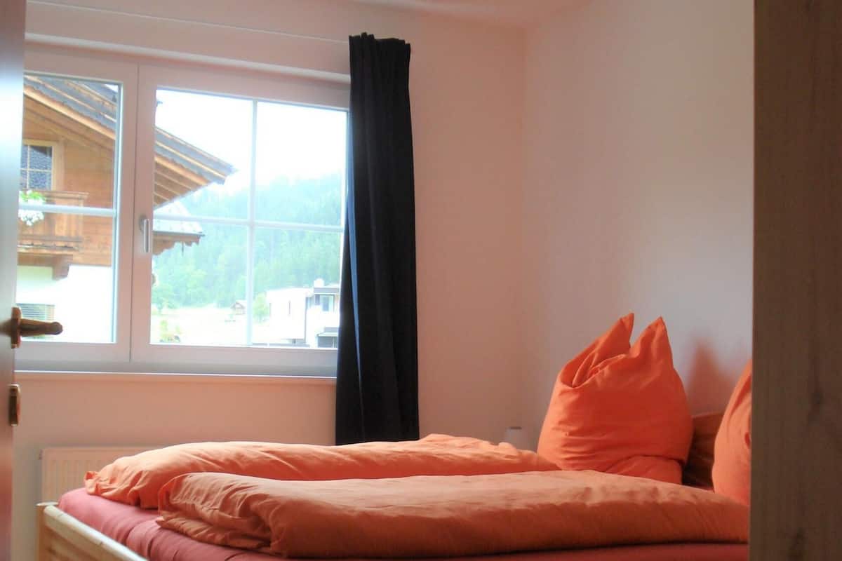 Un letto di legno in una stanza con una finestra e vista su una montagna.