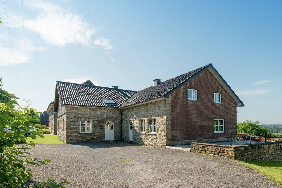 A two-story stone house with a gravel driveway and a brick exterior.