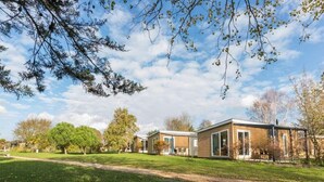 Et moderne hus med to etager, en stor forhave, en indkørsel og en klar himmel.