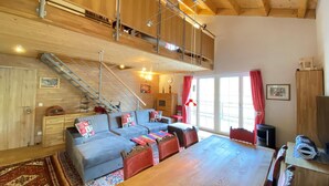 A spacious living area with a wooden ceiling, a large sofa set, a dining table, and a staircase leading to an upper level. - Chalet Salzburg, Dienten (Dienten am Hochkoenig)