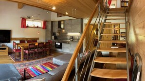 A modern interior with a dining area, kitchen, and a staircase. - Chalet Salzburg, Dienten (Dienten am Hochkoenig)