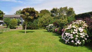 A well-maintained garden with a variety of flowering plants and a lawn in front of a building with a sloped roof. - Modern Apartment in Noordwijk Near the Sea (Noordwijk)