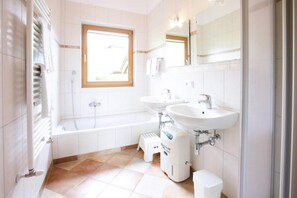 Uma casa de banho moderna com banheira, duas pias, uma janela e um radiador.