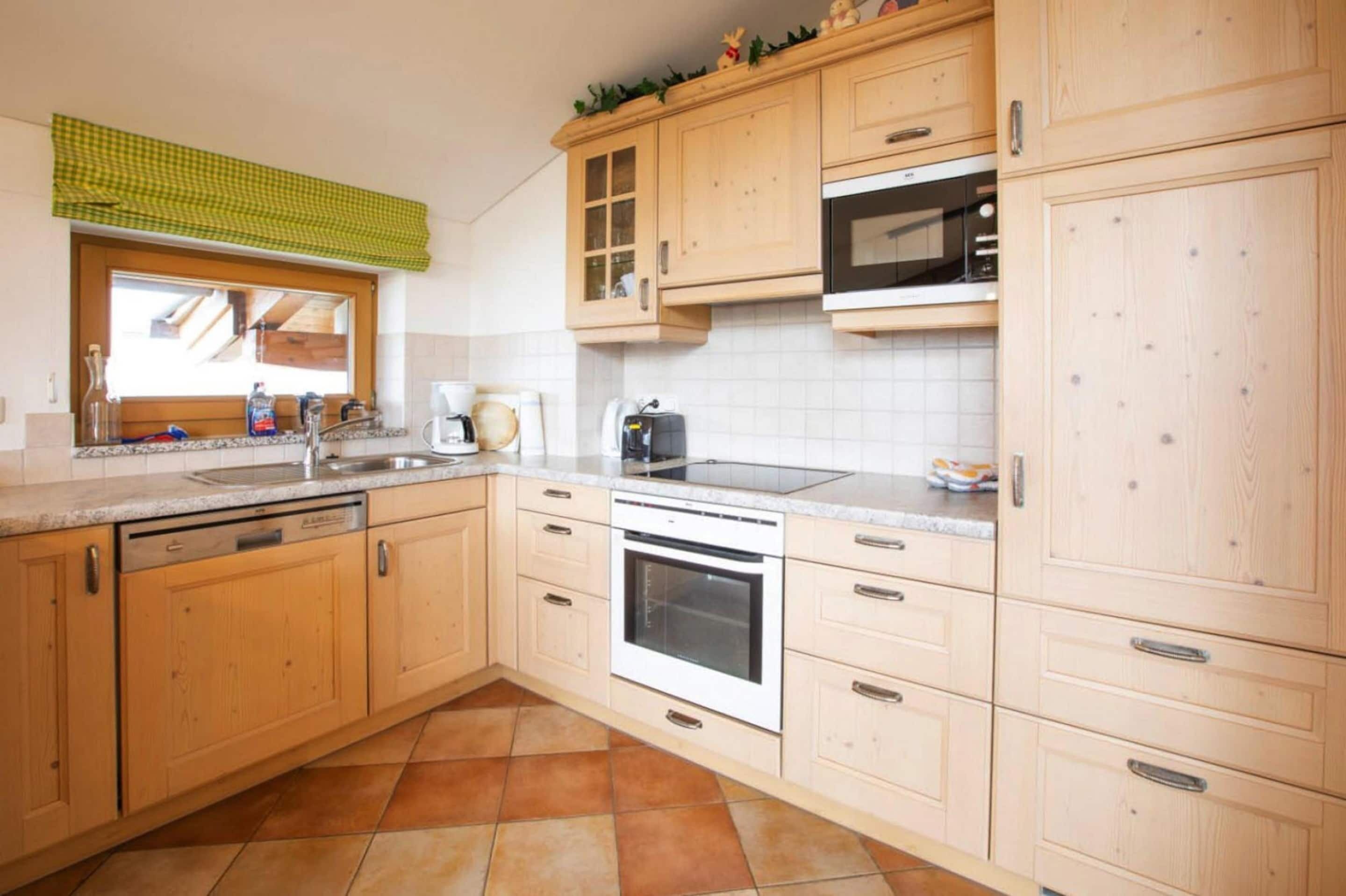A kitchen with wooden cabinets, a microwave, an oven, and a sink.