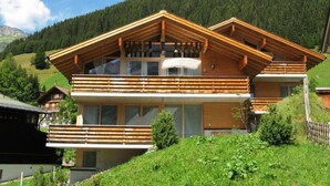 A modern wooden chalet with a balcony, large windows, and a view of a forested mountain. - Holiday Flats Barlerhof, Konigsleiten (Wald im Pinzgau)