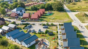 An aerial view of a residential area with multiple houses, a playground, and a road. - Chic Holiday Homes for up to 6 People in Ustka (Ustka)
