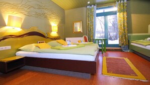 Habitación de hotel con una cama grande, mesitas de noche, una mesita pequeña y una ventana con cortinas.