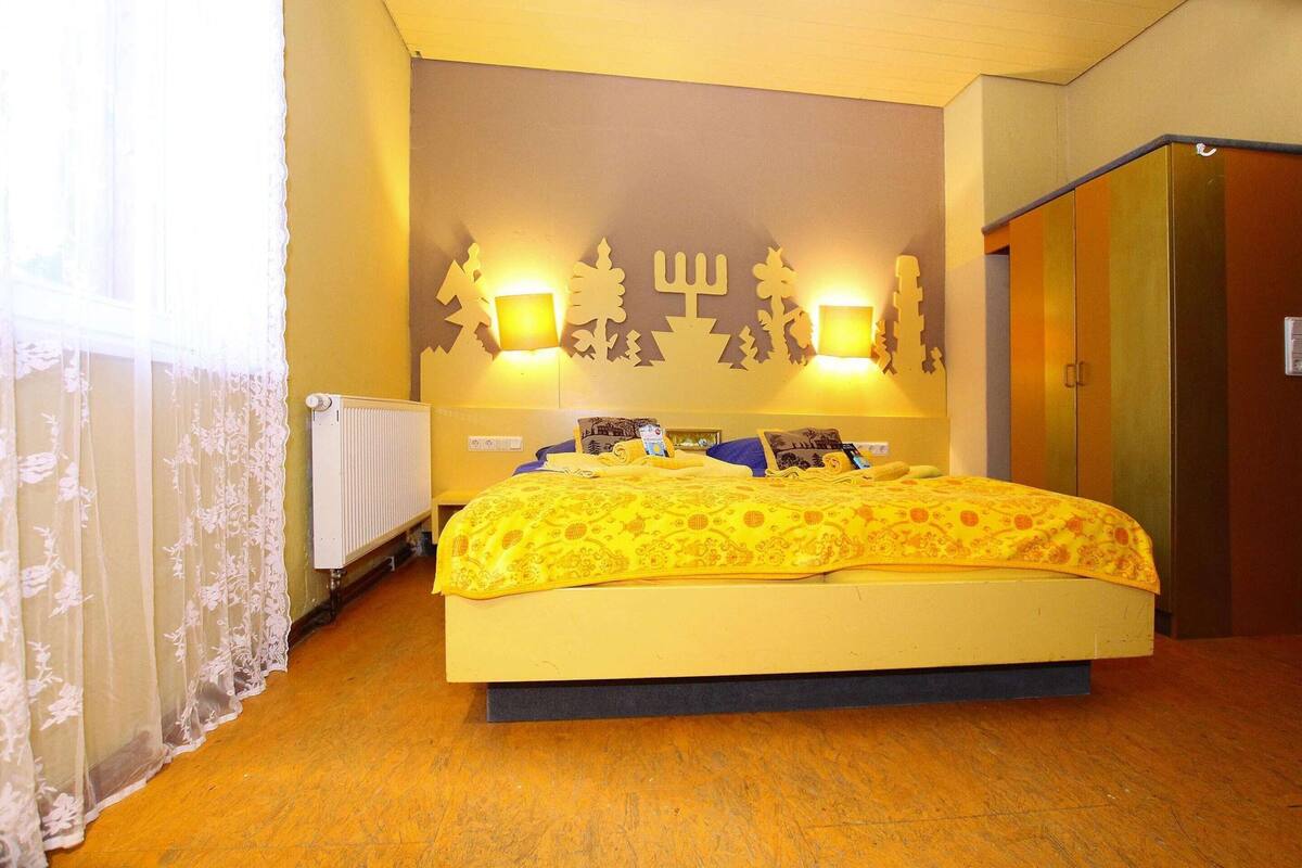 A bedroom with a bed, a radiator, a wall with decorative lights, and a wardrobe.
