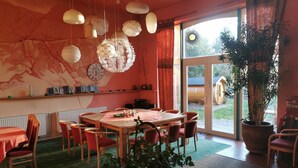 Un comedor acogedor con una mesa de madera, sillas rojas y una planta grande en maceta.