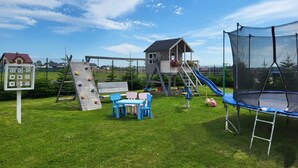 A playground with climbing structures, a slide, and a trampoline. - Comfortable Premium Class Apartment, Shared Swimming Pool, Gaski (Mielno)