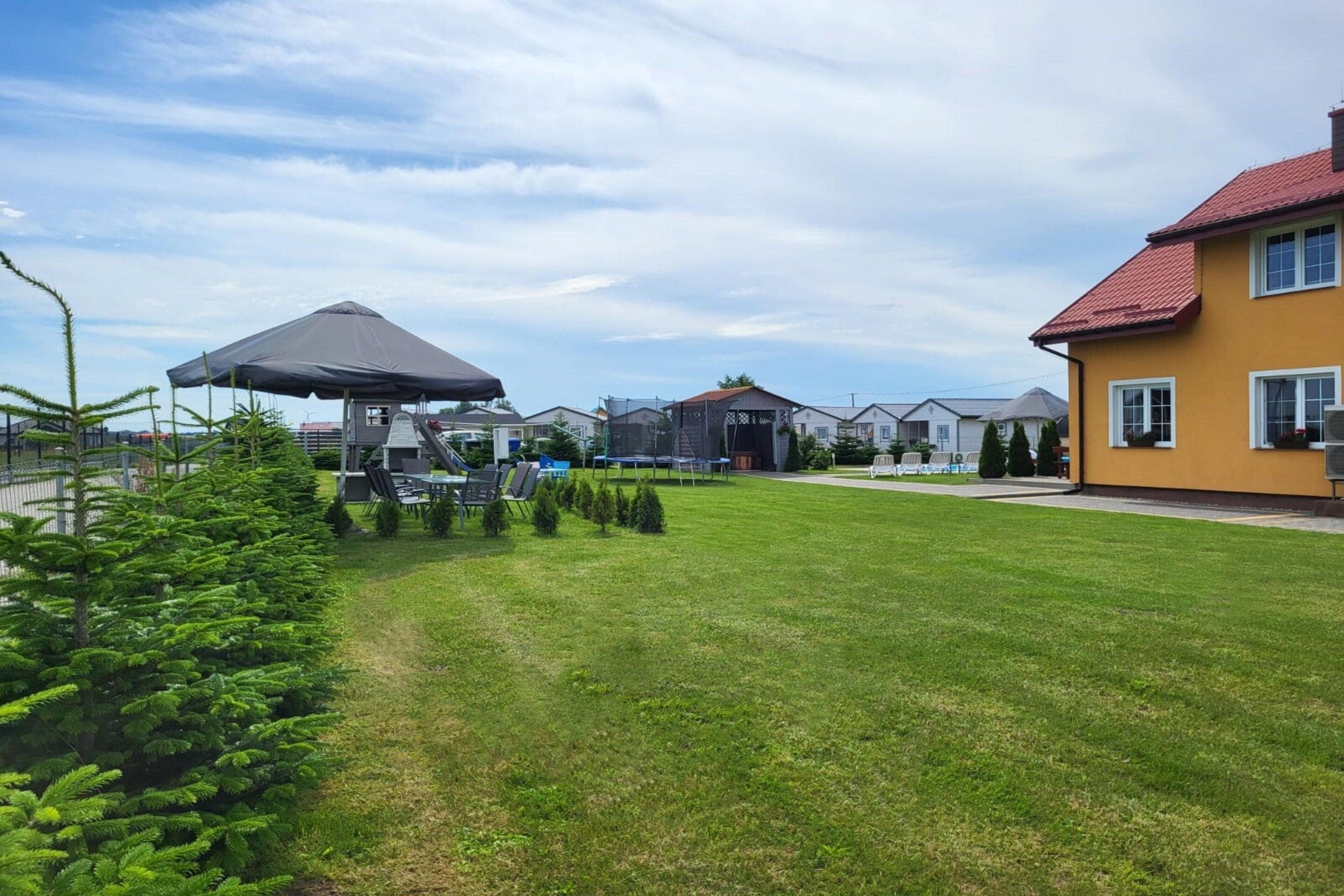 A residential area with a well-maintained lawn, a covered outdoor seating area, and houses with red roofs.