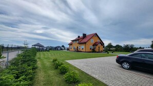 A large yellow house with a red roof, surrounded by a well-maintained lawn and a paved driveway. - Comfortable Premium Class Apartment, Shared Swimming Pool, Gaski (Mielno)